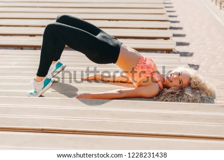 Picture of sports woman exercising among benches in summer day