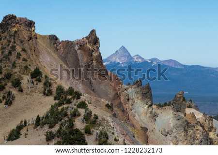 rocky spires and crumbling rocks at the top of Crater Lake with Mount Thielsen in the background