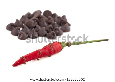 Image of chocolate kisses with red hot chili pepper over the white background