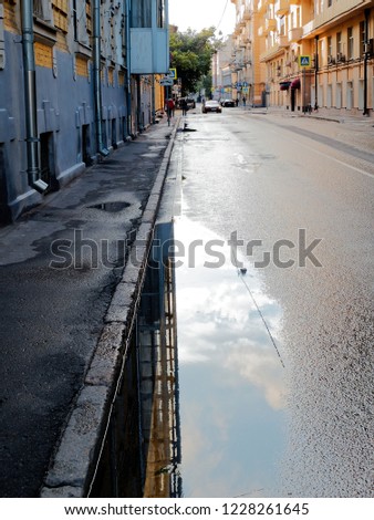 Picture of the street with the  dramatic sky reflecting in the water puddles