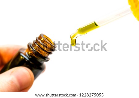 Hand holding bottle of Cannabis oil in pipette isolated on white Royalty-Free Stock Photo #1228275055