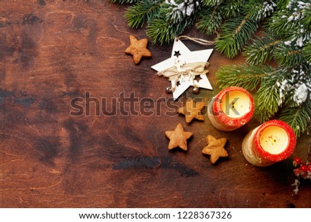 Christmas decor, candles and fir tree branch covered by snow on wooden background. Top view xmas backdrop with space for your greetings