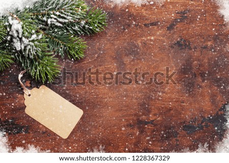 Christmas fir tree branch covered by snow on wooden background. Top view xmas backdrop with space for your greetings