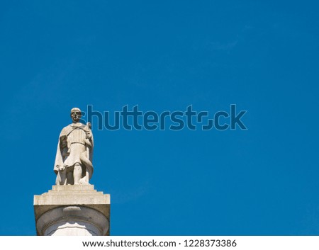 A statue on a column in front of a bright blue sky and without clouds
