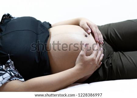 Pregnant woman holding hands on her belly. 36 weeks of pregnant.
