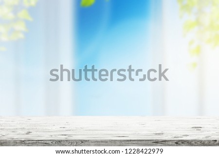 Spring green leaves with blue sky and sunlight and wood floor. Natural background