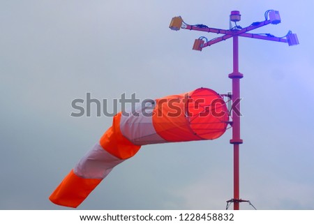 Orange-white windsock against the background of the cloudy sky. bad weather, perhaps storm. Toning