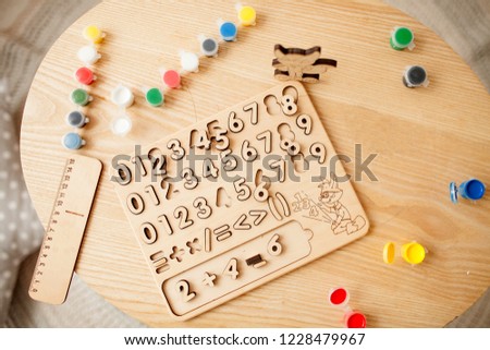 Wooden numbers and a ruler are on the table among the colorful paints. Top view.