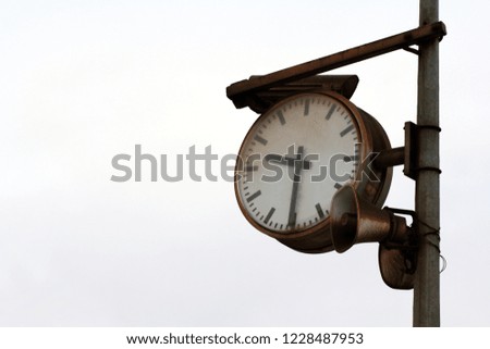 Old rusty clock and loudspeaker on a pole. Railway clock