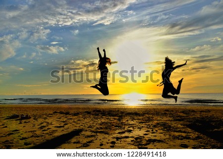 Young women jumping on the beautiful sand beach with the shadow morning light on a wonderful, relaxing holiday.Travel together. silhouette image.