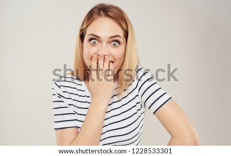 woman striped t-shirt closed mouth with her hands a surprised look                       