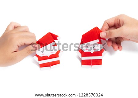 Girls hand holding a Santa origami on white background.
