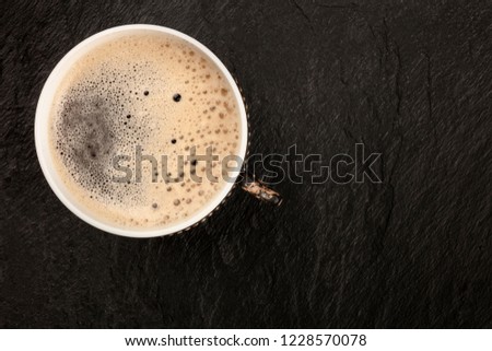 An overhead photo of black coffee in a vretro cup, shot from above on a dark background with copy space