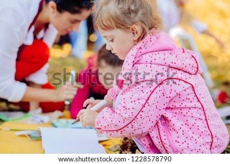 Cute little child girl learn to drawing, children painting in the park. The concept of a happy family.