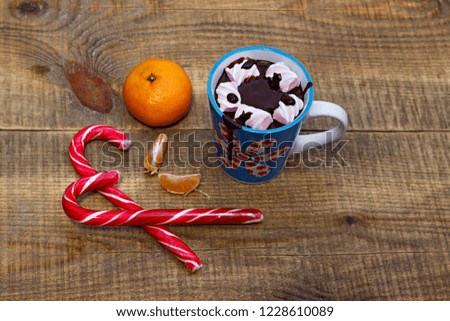 Hot chocolate with candies and marshmallows, tangerines on a wooden background. New Year Christmas.