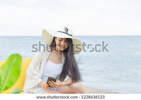 Young pretty asian woman enjoy with cellphone on the tropical beach