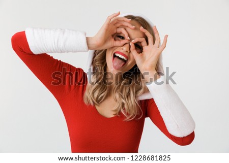 Portrait of a funny blonde woman dressed in red New Year costume standing isolated over white background, showing ok