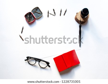 Black ink and ink bottle, white sheet mockup and ink pen on a white background; top view, flat lay; overhead view