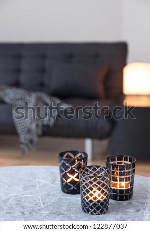Tea-lights in glass candle holders decorating living room with gray sofa. Royalty-Free Stock Photo #122877037