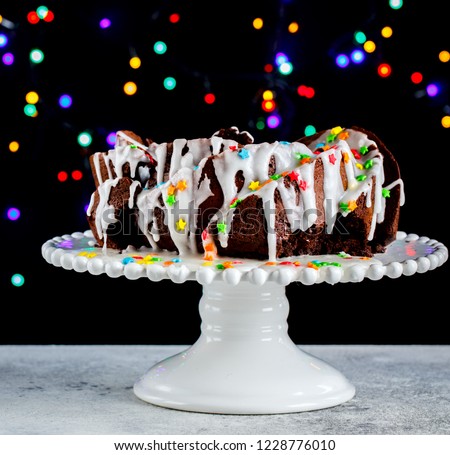 Christmas Chocolate Cake. Bokeh Effect. Festive dessert with glaze Decorated with colorful star shaped confetti.