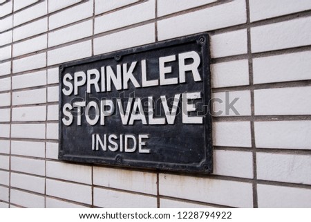 A sign on a wall saying sprinkler stop valve inside