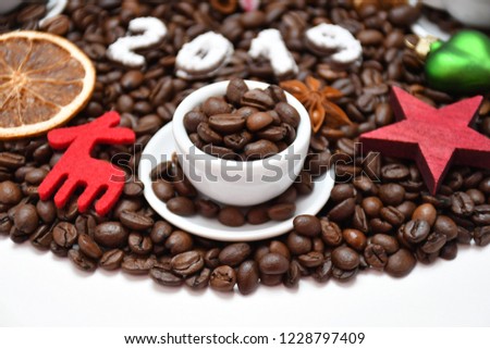 A small cup with coffee beans, coffee beans nearby, digits 2019 made of chocolate & caster sugar, different Christmas-tree decorations,а star, а star-anise, а dried orange slice & two other small cups