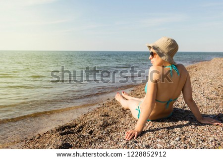 A young girl on the sea coast looking into the distance. Rear view.