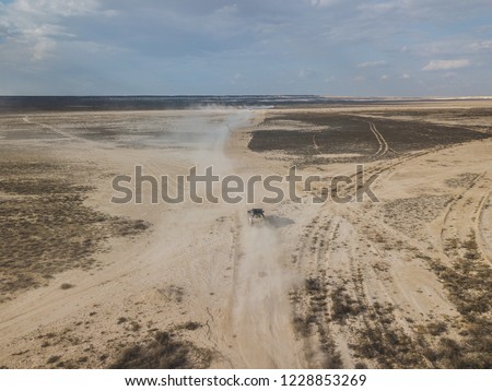 The car crosses the desert leaving dust. Locality in the country of Kazakhstan, similar to Arizona