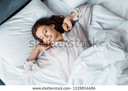 attractive young woman in pajamas waking up in bed in the morning Royalty-Free Stock Photo #1228856686