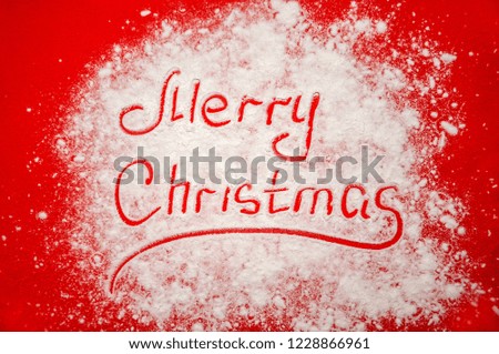 Merry Christmas Written on the Scattered Flour Snow Simulation on Red Background. Minimal Holiday Concept