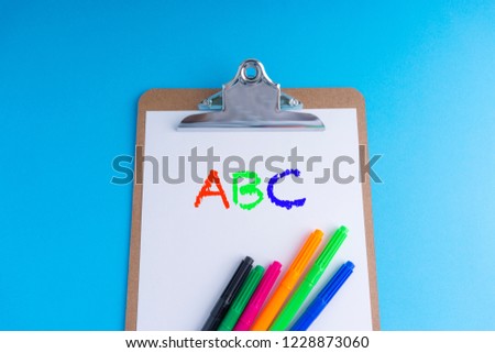 Clipboard and words ABC on blue background with selective focus and crop fragment