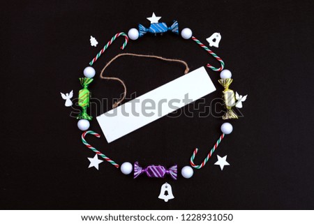 Merry Christmas and Happy New Year decoration on a black background. Text place. Snowflakes, bells, nuts, candy.