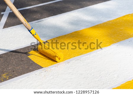 Application Of Road Markings For Pedestrians With Bright Yellow And White Paints. Pedestrian Crossing Over Road. Road Works. Royalty-Free Stock Photo #1228957126