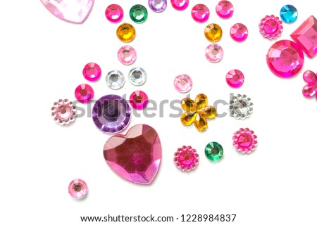 Multicolored rhinestones in the form of hearts and flowers, round rings isolated on a white background Royalty-Free Stock Photo #1228984837