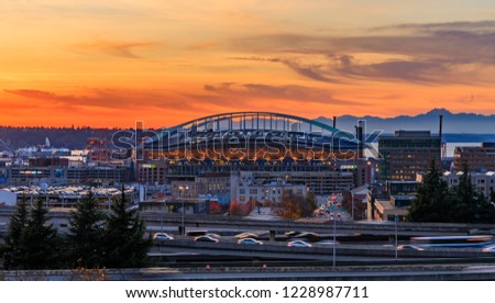 Seattle downtown and Safeco Field  beyond the I-5 I-90 freeway interchange at sunset in the fall with yellow foliage in the foreground view from Dr. Jose Rizal or 12th Avenue South Bridge