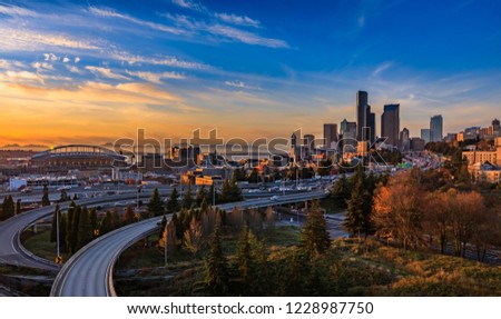 Seattle downtown skyline and skyscrapers  beyond the I-5 I-90 freeway interchange at sunset in the fall with yellow foliage in the foreground view from Dr. Jose Rizal or 12th Avenue South Bridge