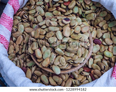 Dried broad beans in wooden bowl, top view and selective focus