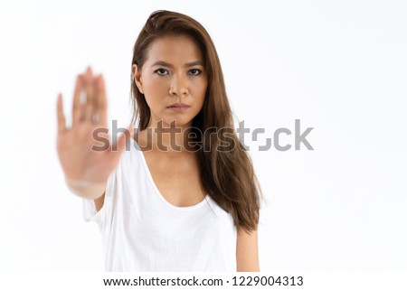 Strict girl showing stop sign. Serious young woman raising hand with open palm in warning gesture. Warning concept