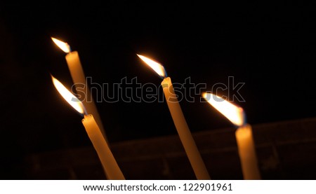 Four thin candles on dark background. Dripping wax.