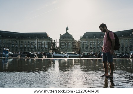 
Young tourist enjoying the city of Bordeaux in France. Playing in the famous square with water mirror. Falling drops. Relaxed and fun time. Lifestyle.