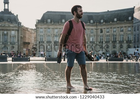 
Young tourist enjoying the city of Bordeaux in France. Playing in the famous square with water mirror. Falling drops. Relaxed and fun time. Lifestyle.