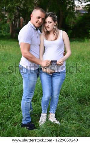 man and woman are holding in their hands on the belly of a pregnant woman screening scan. Happy family. Outdoor photo