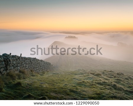 Cloud Inversion over Hadrian's Wall as it runs cross the top of the Whin Sill near Hotbank Crags. Royalty-Free Stock Photo #1229090050