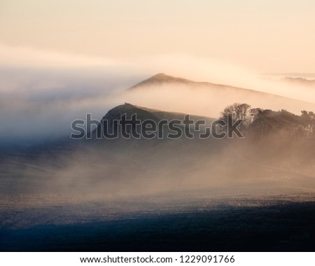 Mist rising over Hadrian's Wall as it runs cross the top of the Whin Sill. Royalty-Free Stock Photo #1229091766