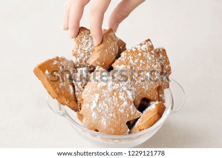 Children holding Christmas cookie.Holiday gingerbread like a new year trees with sugar icing in glass bowl on neutral background