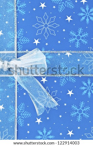 Close-up cropped image of a blue Christmas gift box tied with ribbon.