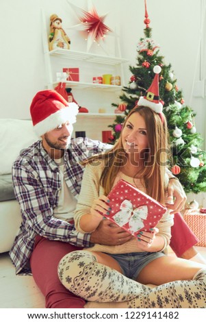 Couple in love sitting near Christmas tree. Christmas and New Year concept.