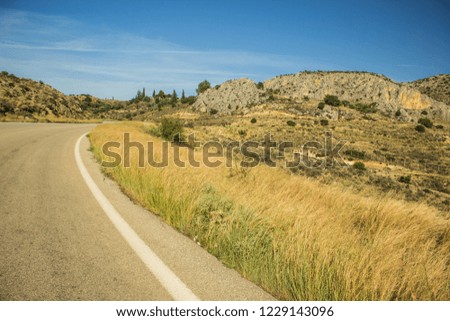 Curved small narrow empty car road in highland scenic mountain landscape in warm dry summer weather