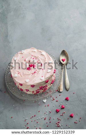 Cake with small hearts and colorful sprinkles with two spoon on gray background. Valentine's day card, St. Valentine's, Mother's Day, Birthday Cake Background with space for text. Vertical.