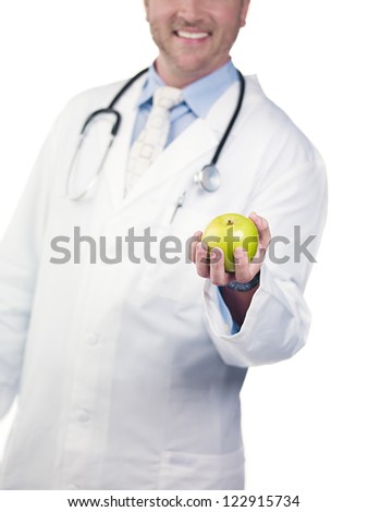 Cropped image of a doctor showing green apple against white background